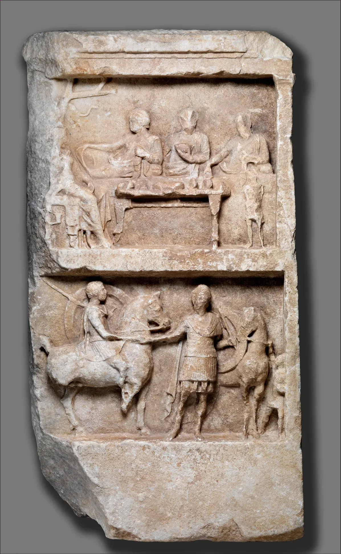 greco-roman funerary stele in two registers with banquet and combat scenes