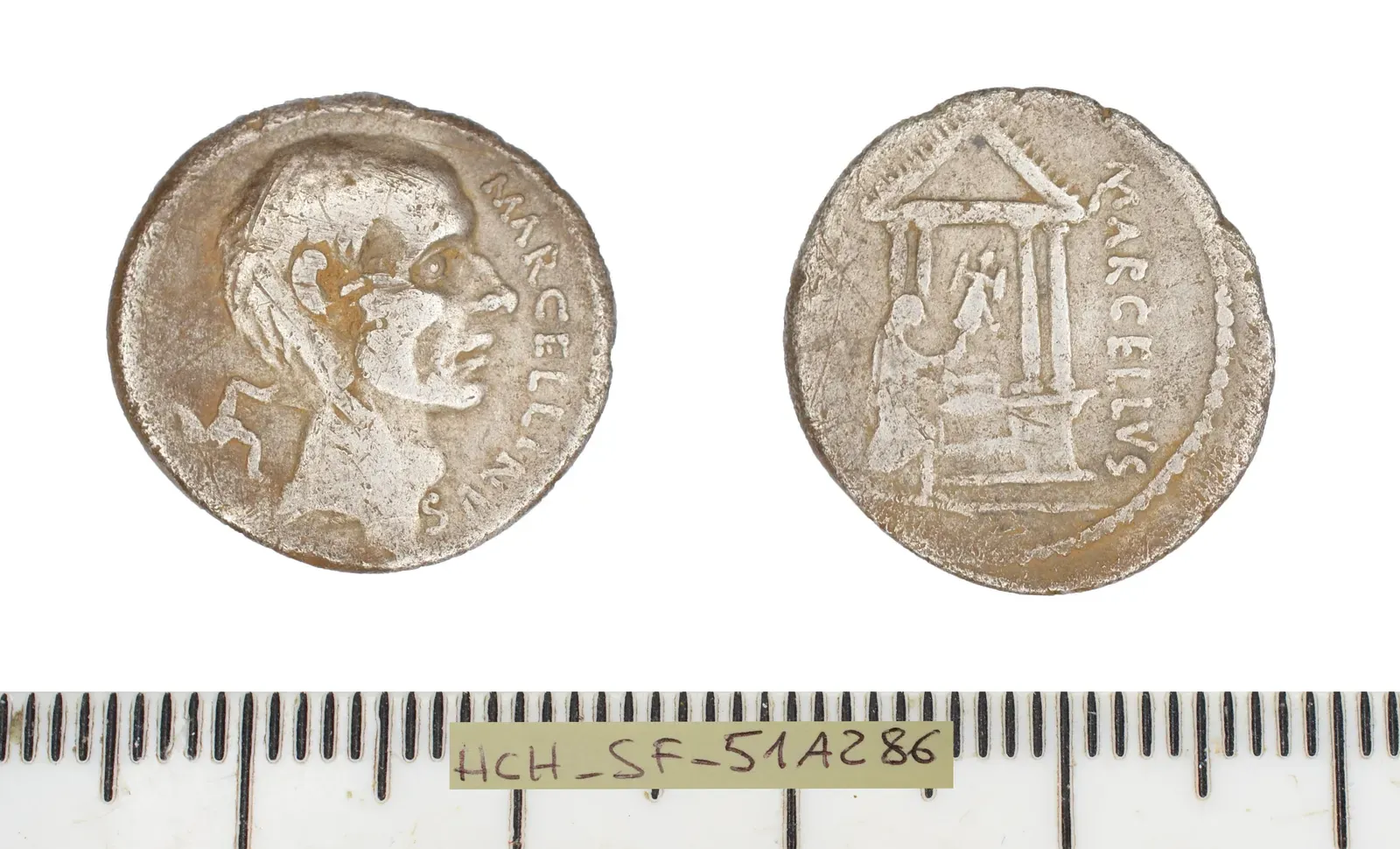 denario romano de plata fotografiado por las dos caras: a la izquierda una cabeza masculina con la leyenda marcellinus; a la derecha una figura con un trofeo de armas ante un templo de cuatro columnas, con la leyenda marcellus; debajo, una regla de medida