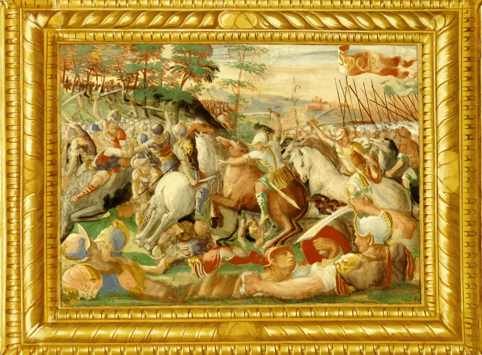 fresco del siglo xvi en un marco dorado: jinetes y soldados chocan al pie de una ladera arbolada, con caídos en primer plano, un estandarte rojo con las letras spqr y, al fondo, agua y una fortaleza