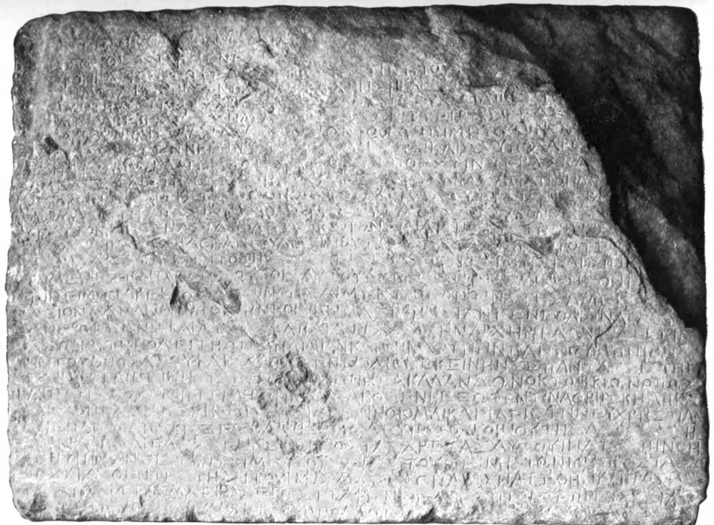 fotografía antigua en blanco y negro de un bloque de piedra desgastado, cubierto de líneas de letras griegas incisas: la inscripción del calendario de priene