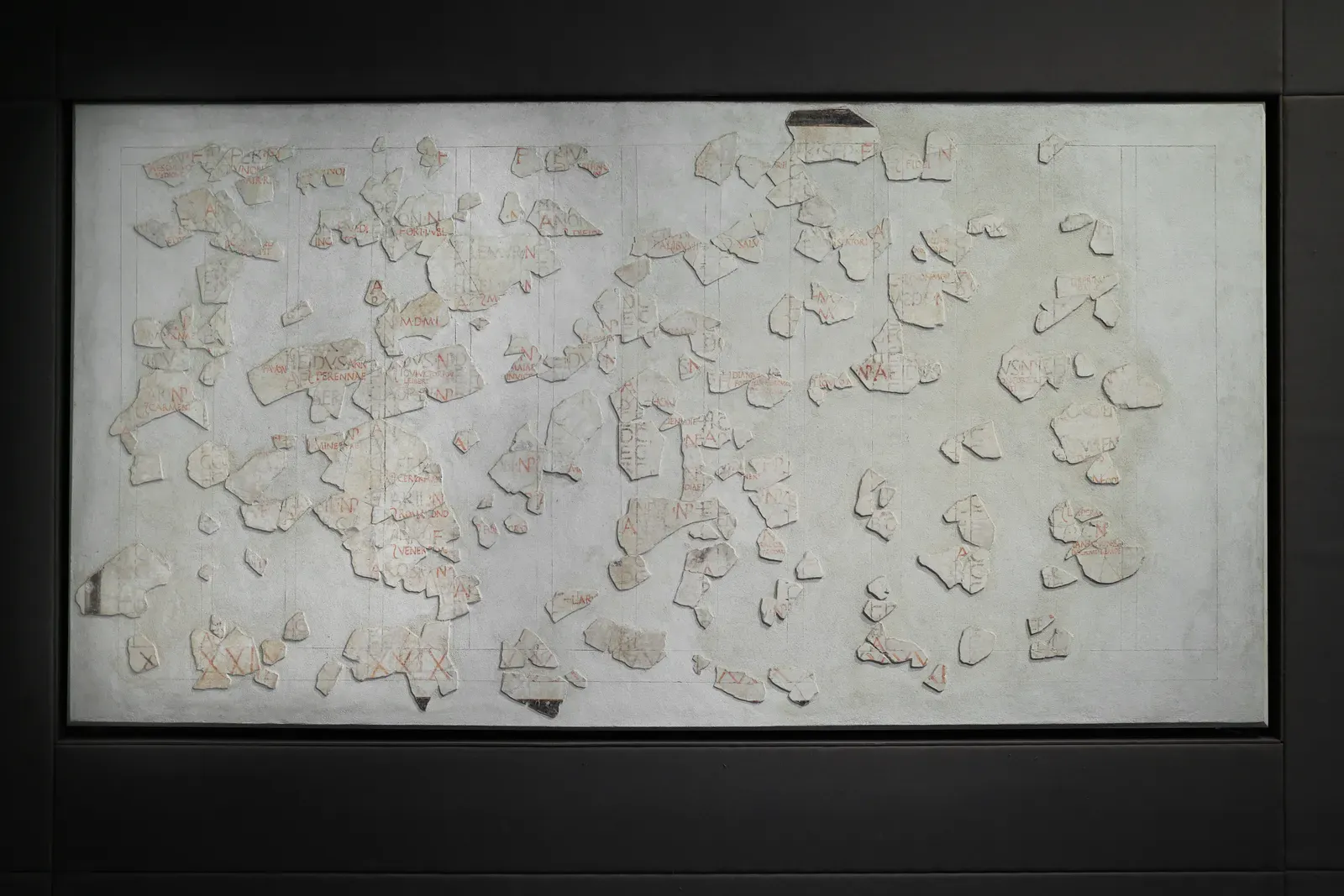 fragmentos del calendario pintado de anzio, con letras rojas y negras, recolocados sobre un panel blanco en el que está dibujada la retícula de las columnas de los meses